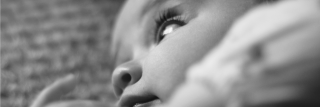 Gros plan en noir et blanc d’un bébé allongé, regard vers le haut