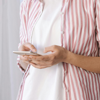 Main d'une personne en chemise rayée utilisant un smartphone