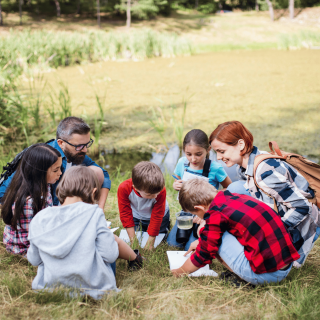 Deux adultes et cinq enfants sont accroupis dans la nature