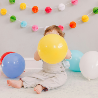 Jeune enfant assis qui tient un ballon jaune dans ses mains